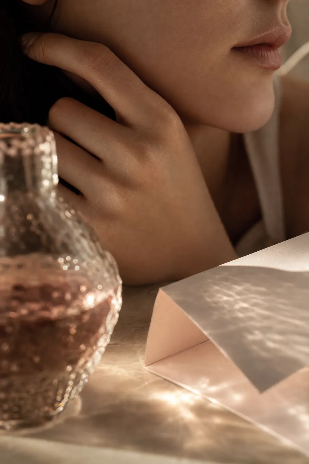 Hands applying skincare serum in soft warm light