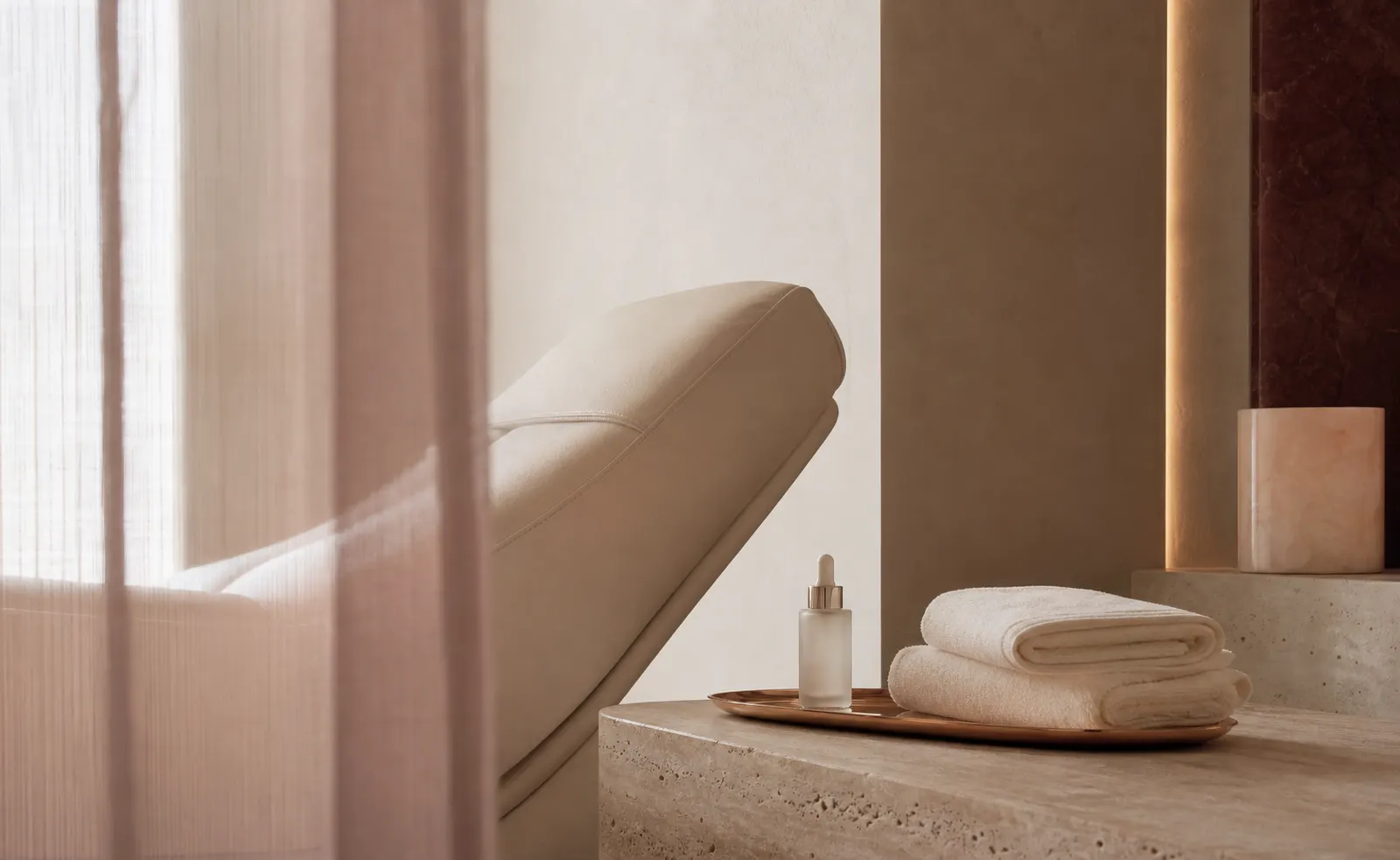 Warm private skin studio with cream chaise and folded towels